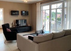Ferienwohnung Schomaker Das Wohnzimmer einer Ferienwohnung mit Sitzmöbeln, TV und einem großen Fenster.